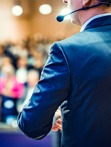 Male speaker in blue suit addressing to an audience